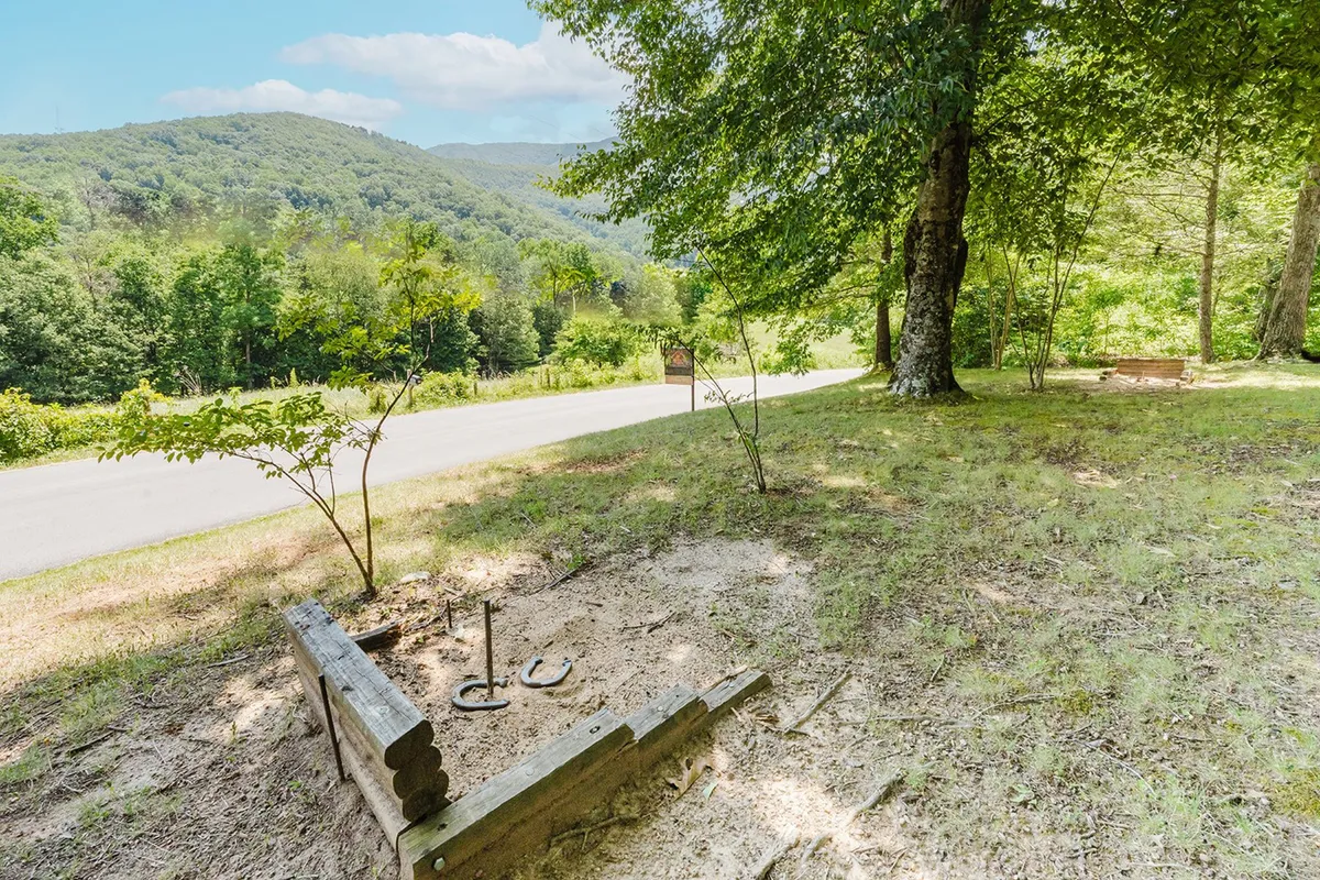 This exterior shot features a horseshoe pit set against lush greenery with a dramatic mountain backdrop. The scene captures the spirit of outdoor fun, relaxation, and togetherness, all within the natural beauty that defines Smoky Mountain adventures.