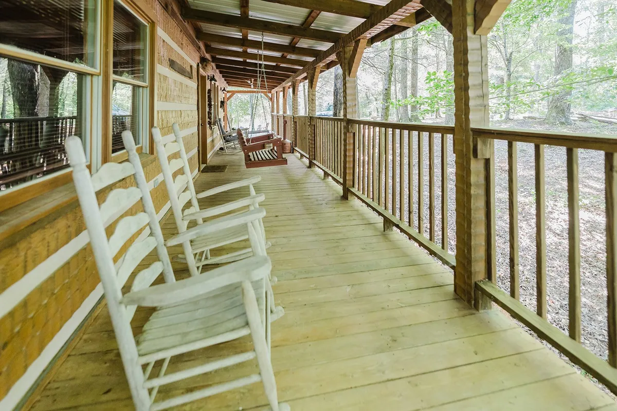 This photo features a pair of rustic rocking chairs on a wooden deck, overlooking natural surroundings. The soft evening light and peaceful atmosphere invite moments of conversation, stargazing, or simply soaking in the tranquility of the Smokies.